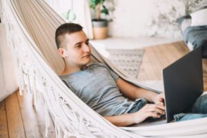 A young caucasian businessman in headphones works on a laptop