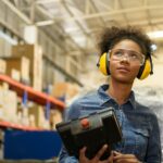 A young female worker is controlling a mechanical robot.