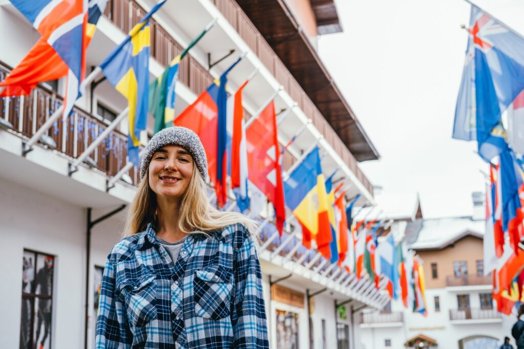 Outdoor portrait young woman standing on a square with a lot of government flags.